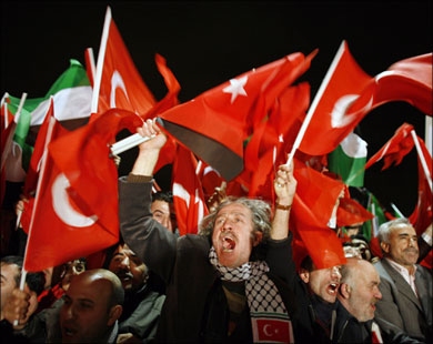 آلاف الأتراك احتشدوا بمطار إسطنبول لاستقبال أردوغان وهم يحملون العلمين التركي والفلسطيني.