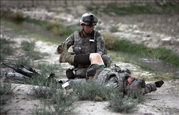 جندي أميركي يساعد زميلاً له أصيب في انفجار عبوة استهدفت آليتهما في لوغار قرب كابول أمس
