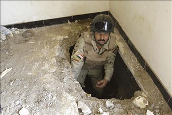 جندي عراقي يخرج مواد كيميائية تستخدم في صنع المتفجرات من حفرة في منزل في حي الحسين في بغداد أمس