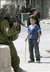 جندي من الاحتلال يصوّب بندقية نحو طفل فلسطيني على أحد المعابر العسكرية في مدينة الخليل في الضفة الغربية أمس الأول.
