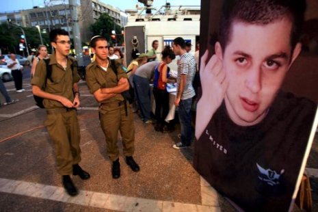جنديّان إسرائيليّان أمام ملصق لصورة شاليط في تل أبيب في آب الماضي