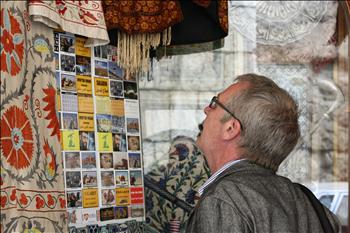 سائح أجنبي يدقق في الصور المعلقة على أحد جدران متجر لبيع السجاد في دمشق القديمة.