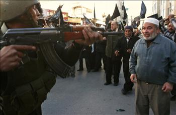 رطي فلسطيني يصوّب رشاشه باتجاه عجوز فلسطيني خلال تظاهرة معادية لأنابوليس في الخليل أمس