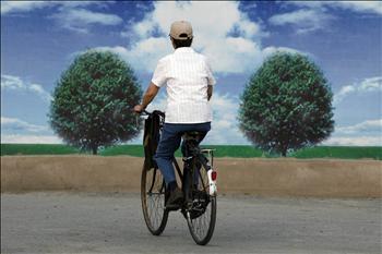 صينية تركب دراجة، تمر الى جانب إعلان يروج لحماية البيئة. في بكين أمس