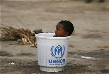 طفل باكستاني يستحم في وعاء مائي مقدم من وكالة الأمم المتحدة للاجئين في مخيم بمنطقة سوكور في ولاية السند أمس