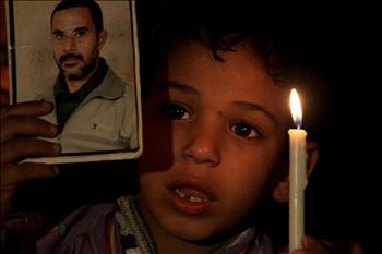 طفل فلسطيني يحمل صورة لوالده الأسير خلال اعتصام تضامني مع الأسرى في مدينة غزة أمس.