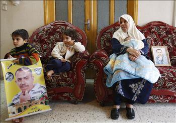 عائلة فلسطينية ترفع صورتين للوالد الأسير نافذ حراز في مدينة غزة أمس