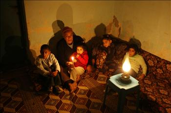 عائلة فلسطينية تجلس حول قنديل بعد انقطاع الكهرباء في مخيم الشاطئ في غزة، أمس، وذلك بسبب عدم توريد الاحتلال الإسرائيلي للوقود اللازم لتشغيل محطة الطاقة 