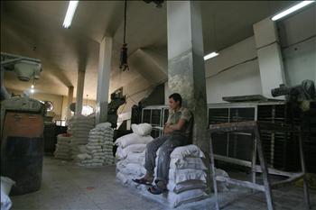 عامل في فرن يجلس على أكياس الطحين، مشاركاً في إضراب أصحاب الأفران في غزة أمس