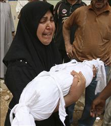 عراقية تحمل جثمان طفلها الذي قتلته غارة أميركية، في النجف أمس