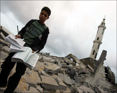 فتى فلسطيني يحمل نسخا من المصحف الشريف جمعها من بين ركام مسجد استهدفه الاحتلال