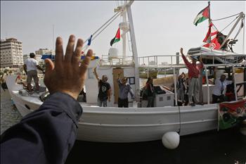 فلسطيني يلوّح مودعاً ناشطين دوليين قبيل مغادرتهم مرفأ غزة أمس متوجهين إلى قبرص