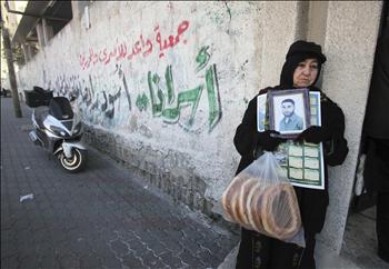 فلسطينية تحمل صورة أحد الأسرى أمام مقر الصليب الأحمر في مدينة غزة أمس.