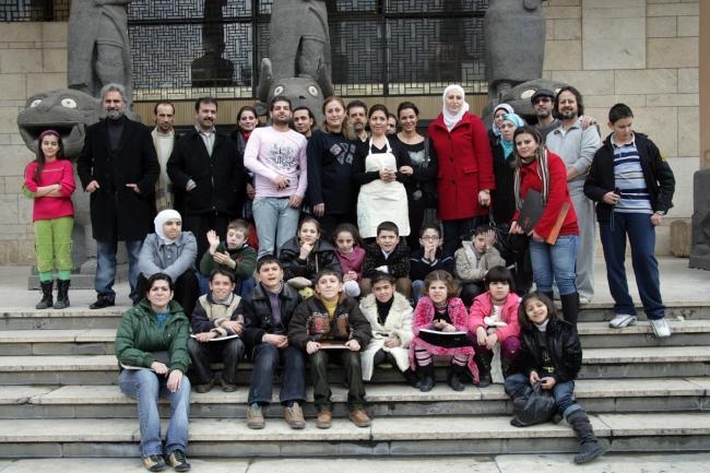 لقطة جماعية للتشكيليين المشرفين على الورشة مع الأطفال أمام مدخل متحف حلب.