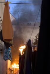 مستوطنون يراقبون منزلاً فلسطينياً بعدما أحرقوه في الخليل أمس
