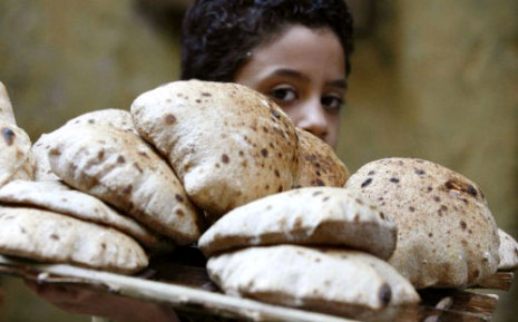 مصري يبيع الخبز في ظلّ ارتفاع الأسعار بعد رفع الدعم الحكومي عن الطحين.