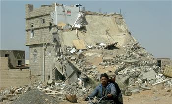 يمنيان يمران امس قرب مبنى مهدم في صعدة، كتب عليه الحوثيون عبارة «هذه هي المساعدات الأميركية لليمن».